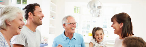 Multi-generational family gathered around a table laughing