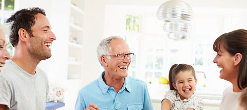 Multi-generational family gathered around a table laughing