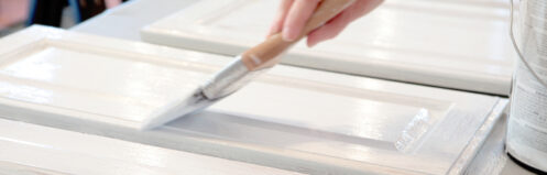 Close up of someone painting their kitchen cabinets white