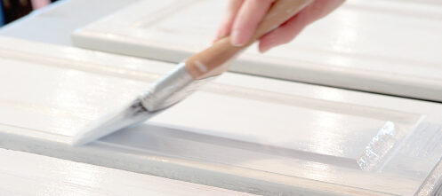 Close up of someone painting their kitchen cabinets white