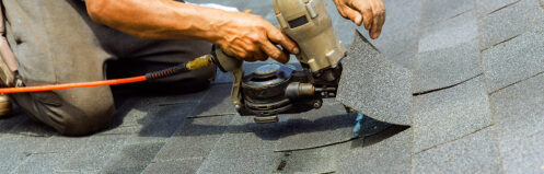 Installer stapling shingles onto a roof