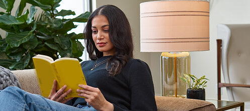 Woman reading a book relaxing on her couch