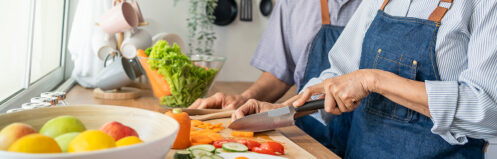 Couple using cutlery to chop vegetables