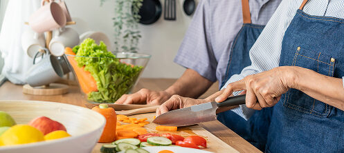 Couple using cutlery to chop vegetables