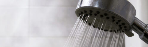 Shower head running steaming hot water