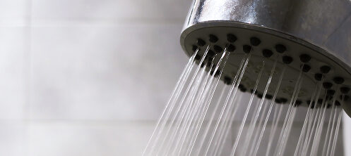 Shower head running steaming hot water